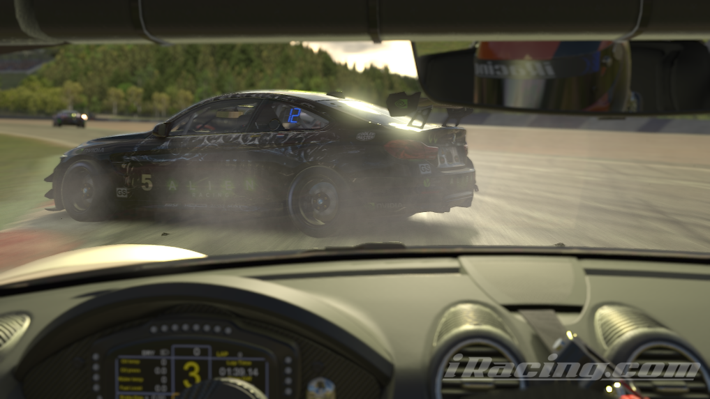 A black BMW M4 GT4 race car with the number "5" visible on its side. The car is angled, and there's a significant amount of white smoke emanating from its rear tires, indicating loss of traction and likely drifting or a very aggressive acceleration out of a corner.